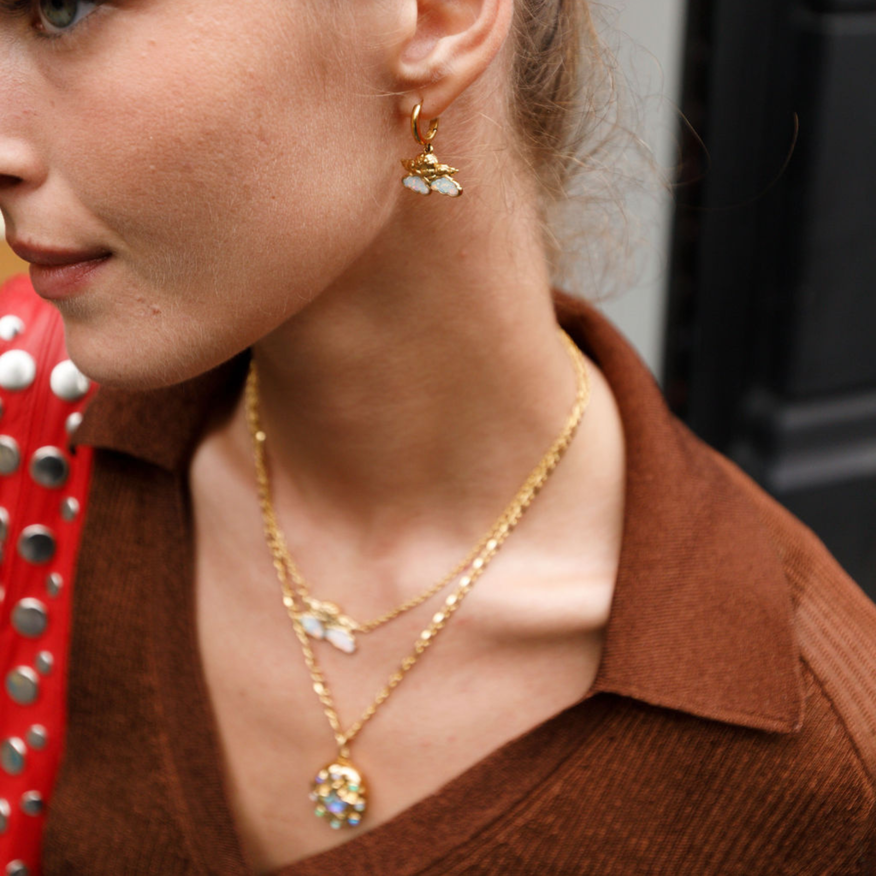 Close-up of a person wearing gold cherub opal earrings.