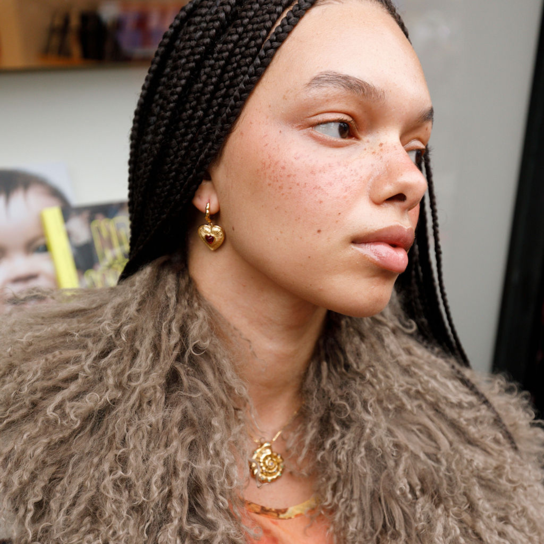 model wearing gold heart locket earrings.