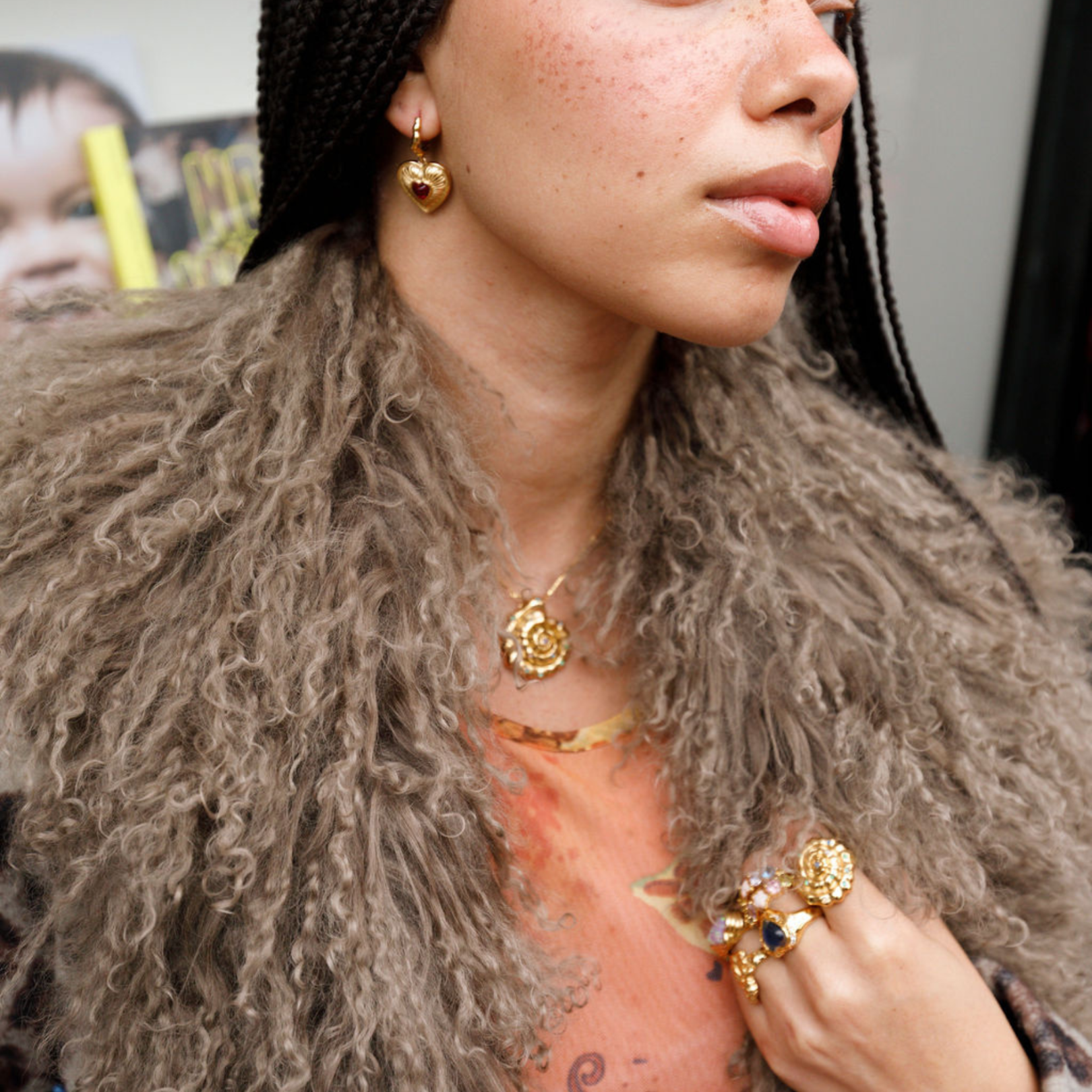 Person wearing gold jewelry including earrings, necklace, and ring.