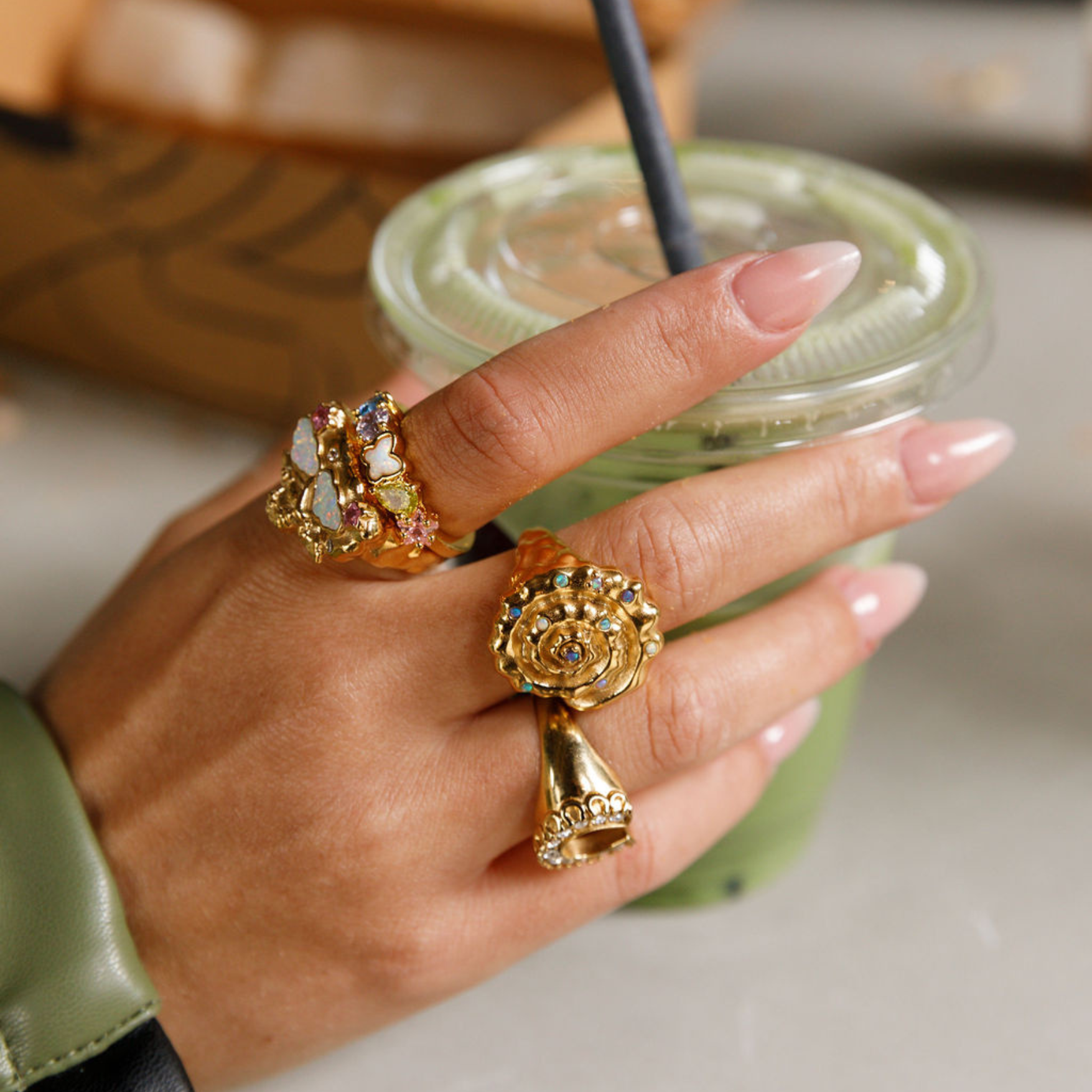 Hand holding a matcha wearing gold rings