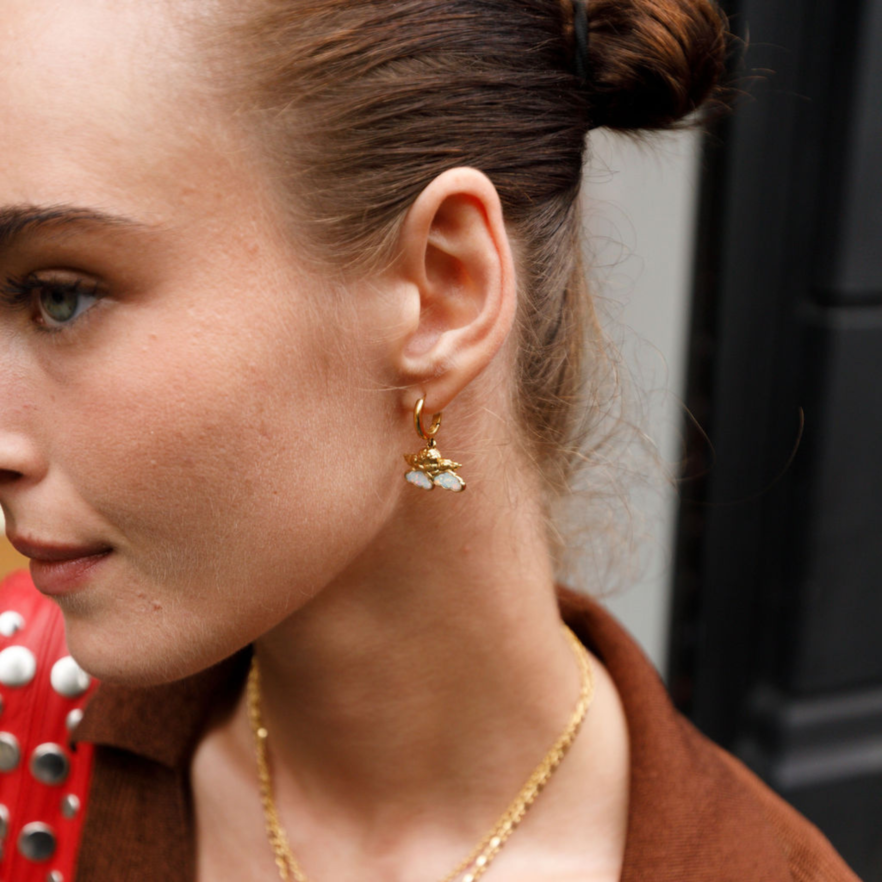 Close-up of a woman wearing gold cherub earrings.