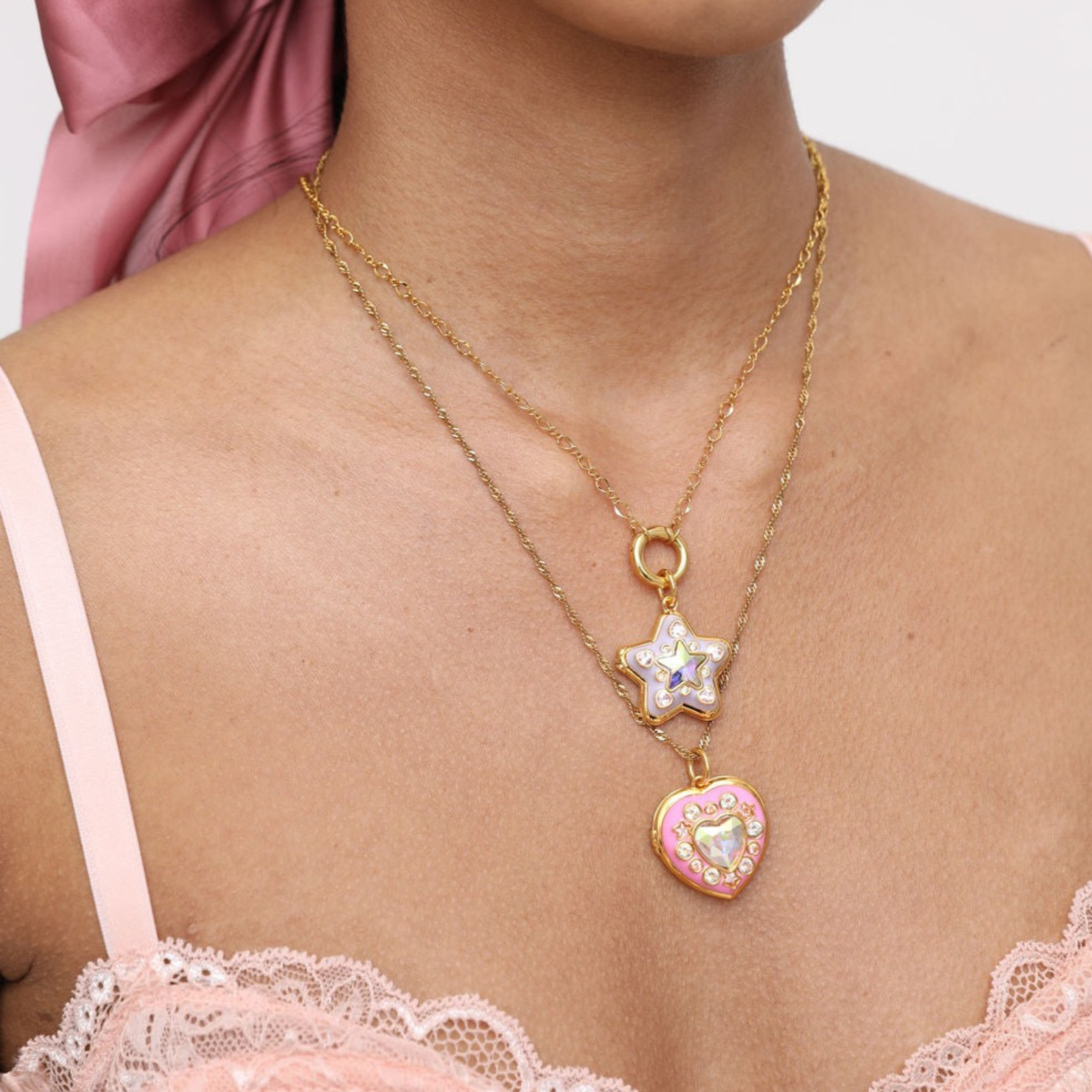 Necklace with star and heart pendants on a person wearing a pink top.