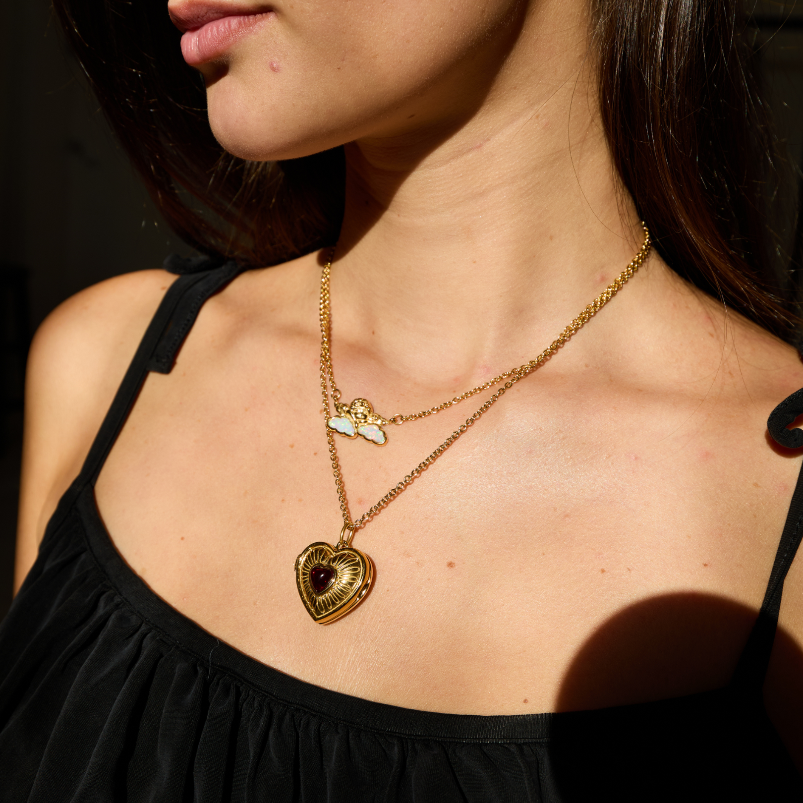 Close-up of a person wearing a gold necklace with a heart-shaped pendant.