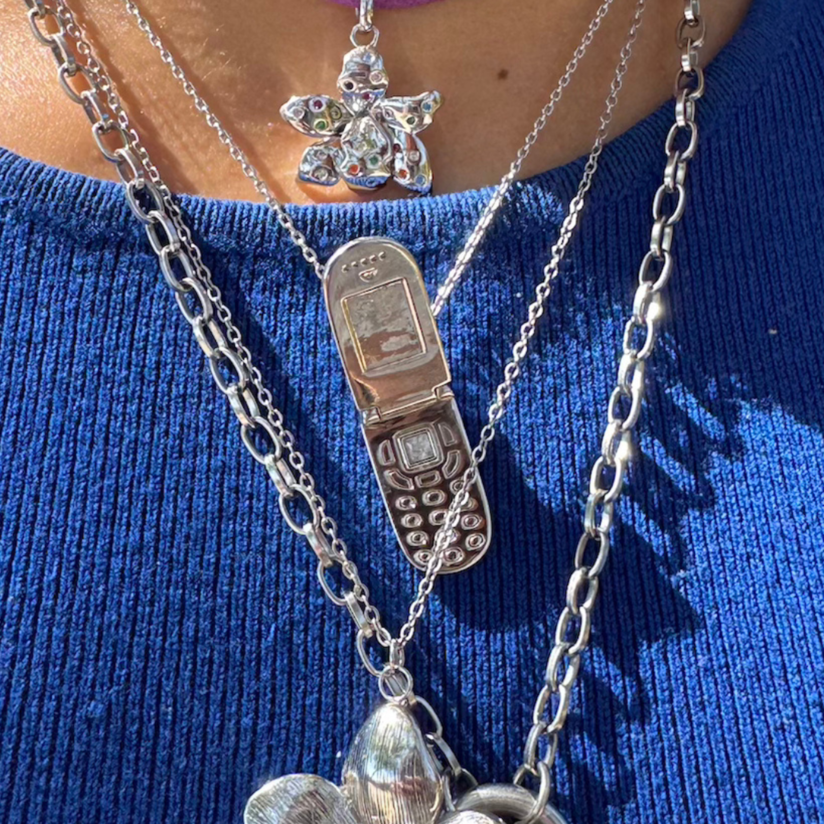 Necklace with phone charm on a blue background.