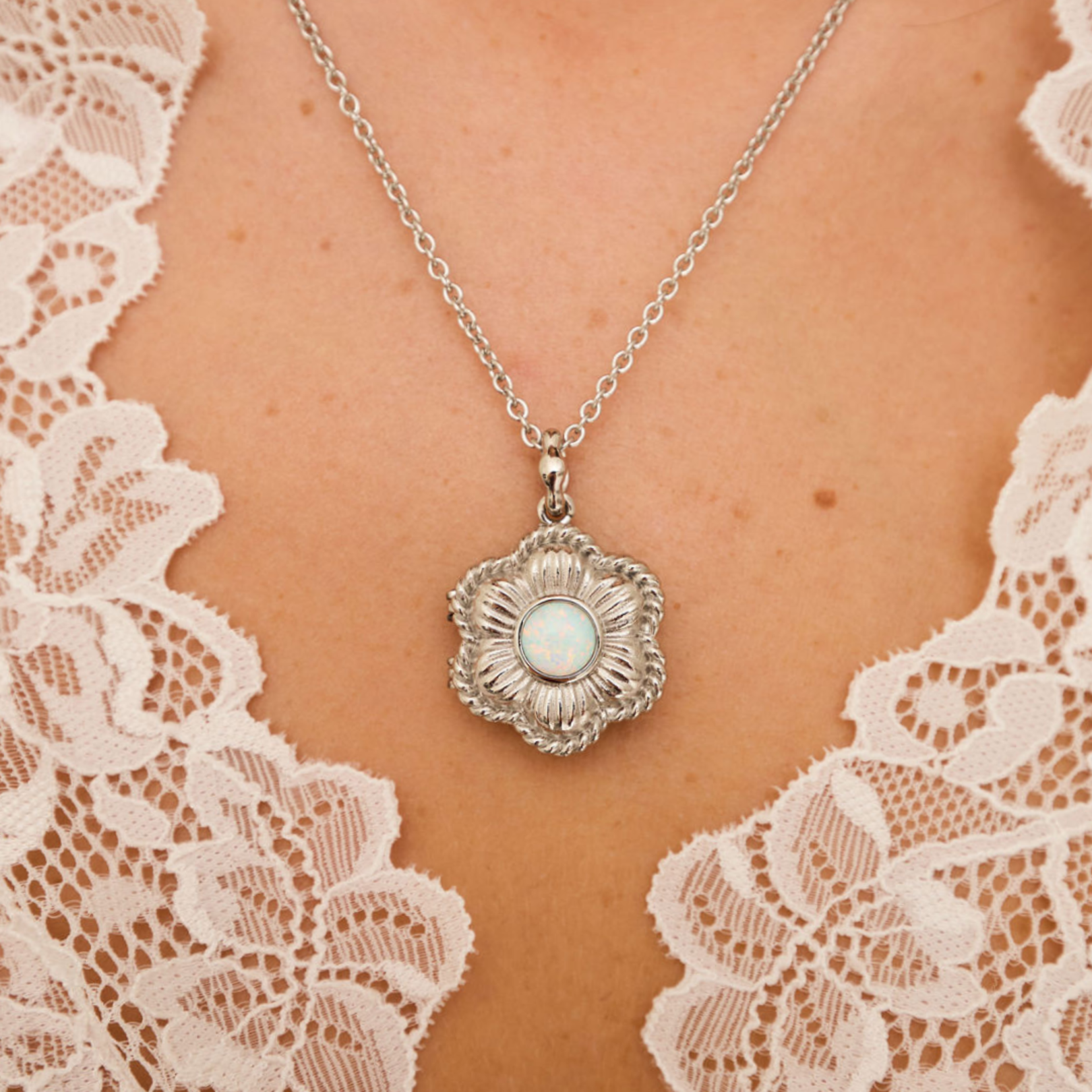 Silver necklace with a pendant on a person wearing lace clothing