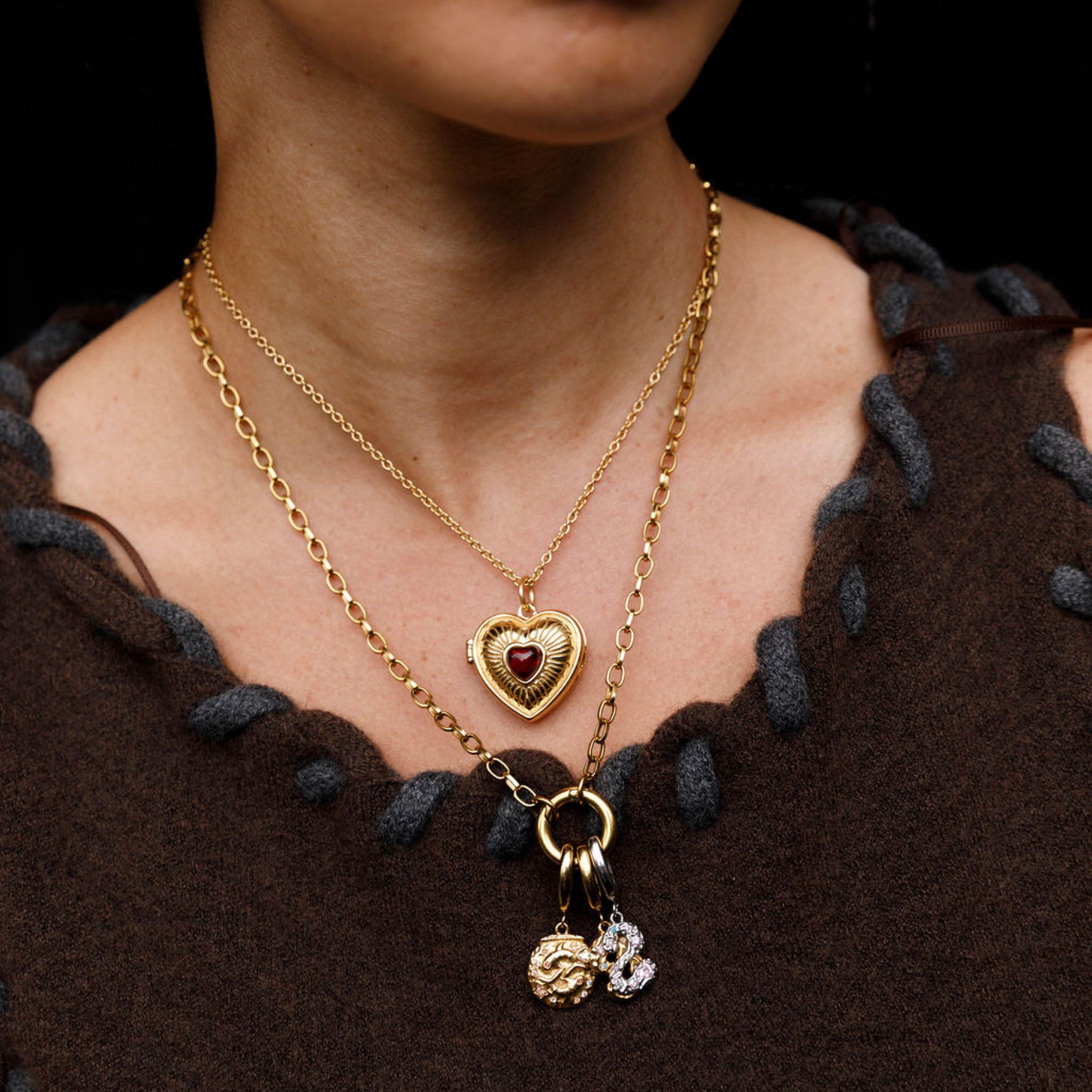 Gold necklace with heart pendant and charms on a model.